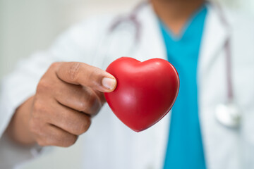 Doctor holding a red heart in hospital ward, healthy strong medical concept.