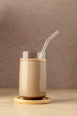 Glass of chocolate shake drink with protein powder scoop and glass straw.