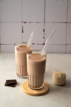 Two glasses of chocolate protein shake drink with glass straws