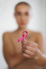 Close-up of woman holding pink ribbon, concept of breast cancer awareness.