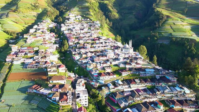 Cinematic drone shot showing colorful buildings called Nepal van Java on mountain during sunset time in Indonesia