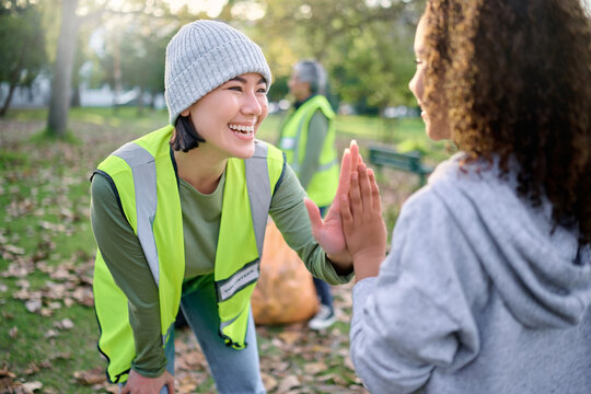 High five, volunteer woman and child cleaning garbage pollution, waste product or community environment support. Teamwork celebration, NGO charity and eco friendly kid happy with nature park clean up