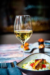 white wine glass with grilled salmon fish fillet with creamy ptitim on table