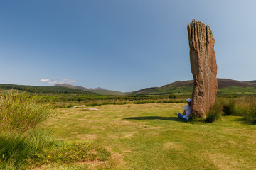 Person seated against standing stone, Machrie Moor standing stones, Isle of Arran, Scotland.