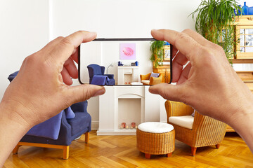 Augmented or virtuel reality concept: hands holding smart phone with AR interior decoration app, showing the living room with added canvas print.