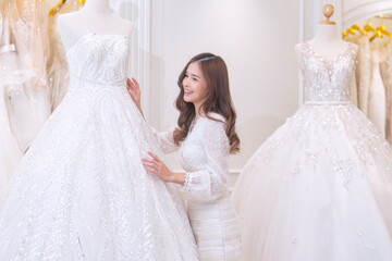 Naklejka premium Women happy see many wedding dresses on shelf and in hands choose dresses for the wedding day