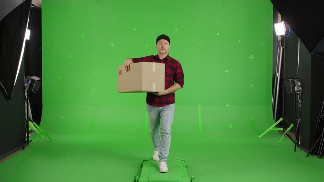 Caucasian man carrying a big paper box walking forward on a chroma key. Delivery concept. Forward view