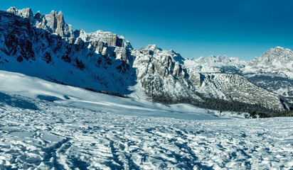 Mountain peak and snowy valley in winter season against a beautiful sunny blue sky