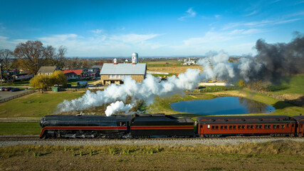 Obraz na płótnie Canvas Aerial Parallel View of a Restored Antique Steam Passenger Train Traveling Thru The Countryside on a Sunny Autumn Day