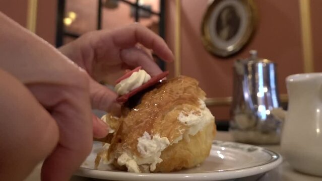 Copenhagen, Denmark A person uses a fork to cut a fastelavnsbolle, a speciality Lent pastry on a plate at a cafe.