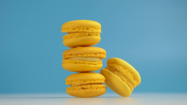 Close-up, yellow macarons, sweet cookie spinning on blue background, 4k slow motion