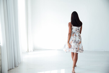 a brunette woman standing with her back in a white room