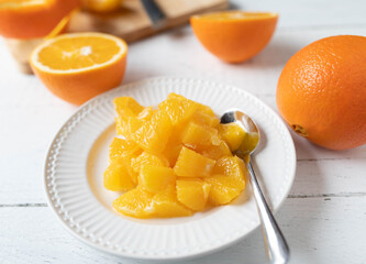 Fresh chopped oranges on a white plate with spoon. Healthy fruit dessert or snack. closeup and...