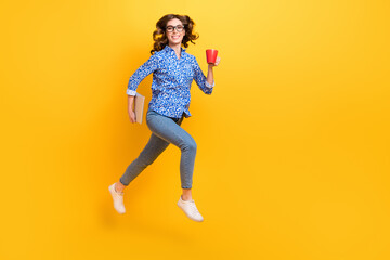 Fototapeta na wymiar Full body profile portrait of excited active lady hold netbook coffee mug jumping isolated on yellow color background