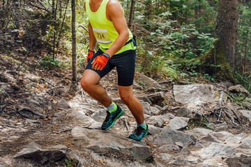 athlete runner run uphill on trail of rocks and roots