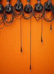 Audio, cables and mockup on an orange wall background in a music studio for recording or sound...