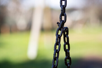 Playground, detail of iron chain, park background out of focus.