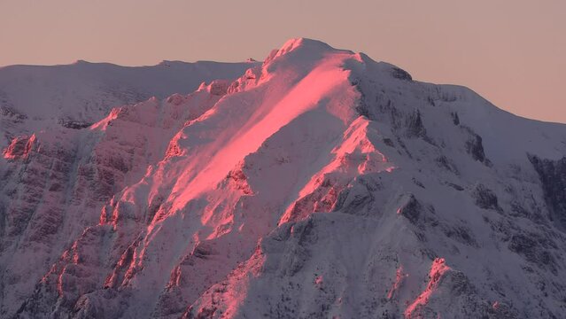 Winter scenic view of first rays of the sun illuminate the peak of Bucsoiu Mare in the Bucegi Mountains covered by snow. 4k video