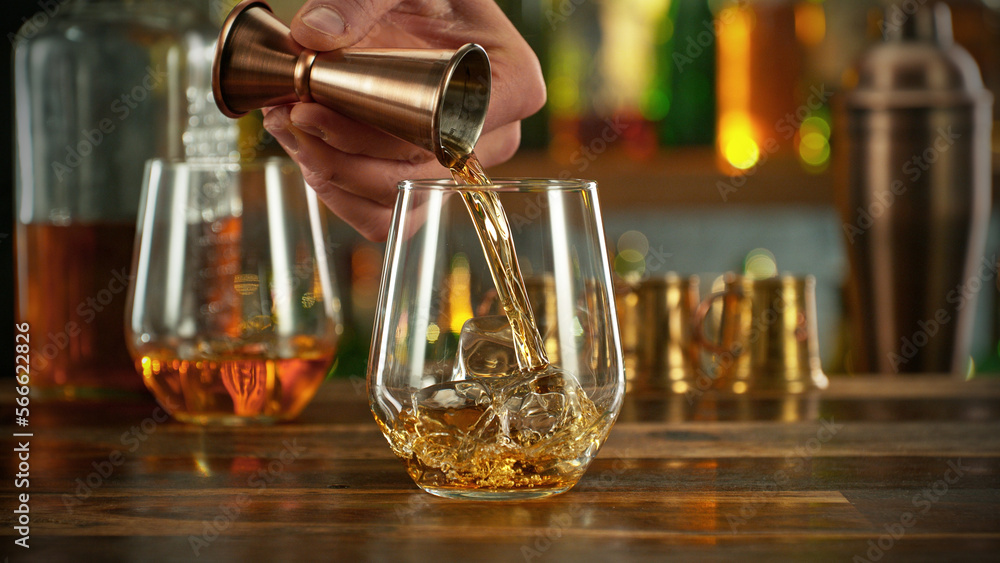 Wall mural Detail of pouring whiskey into glass with ice.