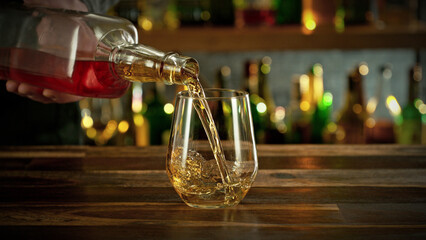 Detail of pouring whiskey into glass with ice.