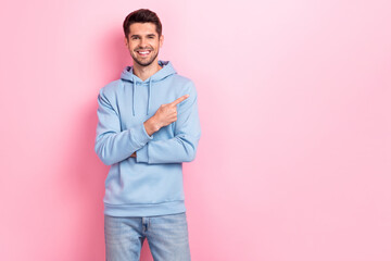 Fototapeta premium Portrait of good looking man arm demonstrating empty space buy new collection trendy clothes low prices isolated on pink color background