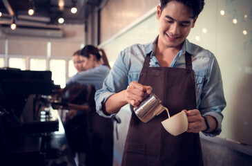 Young barista adept in champion coffee brewing, creating latte art in a cup of coffee for a customer.