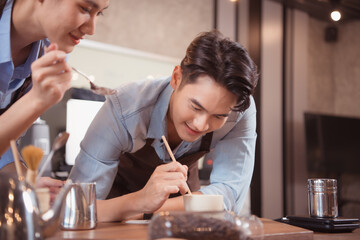 Before competing in the championship level coffee brewing competition, both of the baristas practice their coffee latte makeup techniques to become proficient.