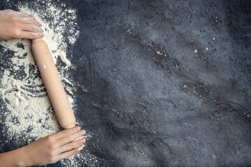 hands keep rolling pin with flour on a dark background. baking background, banner, menu, recipe...