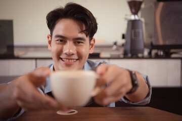 Young barista with the intention of making up a latte coffee to satisfy customers both in appearance and taste, This cup of coffee is ready to be served.