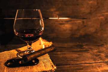 Rum drink with tobacco cigar, handmade on rustic wooden table with coppery colors and low lighting