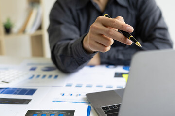 Businessman in office working on laptop reading business accounting and auditing report.