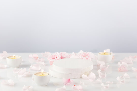 Wooden empty podium with pink roses, petals and candles on white table. Concept scene stage showcase for new product, promotion sale, presentation, cosmetic. Soft image and soft focus style