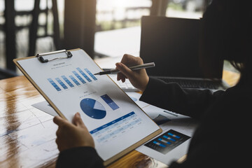 Businesswoman working with financial documents analyzing market growth report and company sales.