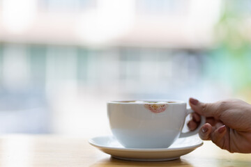 Coffee cup with lipstick stain. Woman holding coffee mug drinking coffee in the morning.