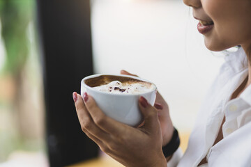 Happy Asian woman drinking coffee in the morning.