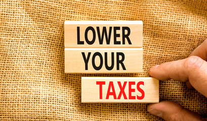 Lower your taxes symbol. Concept words Lower your taxes on wooden blocks on a beautiful canvas table canvas background. Businessman hand. Business tax lower your taxes concept. Copy space.