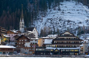 Aerial shot of the frozen lake of Alleghe, houses and snowy town, snow on the roofs. Water lying on the doomites and on Mount Civetta.