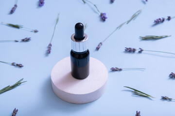 Cosmetic oil in pipette bottle with lavender flowers on colored background