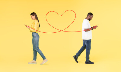 Online Romance. Multicultural Couple Messaging On Smartphones While Walking Over Yellow Background