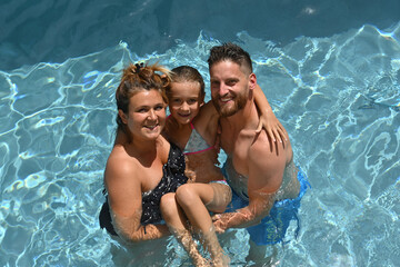 couple with child swimming in pool