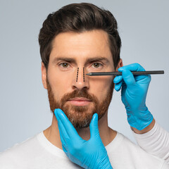 Rhinoplasty concept. Handsome middle aged man with marking on his nose standing on grey background,...