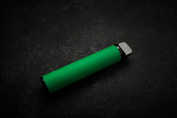 Disposable electronic cigarette of green color, on gray background