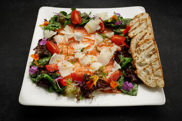 Salmon carpaccio with cheese, tomatoes, and crouton, on a plate