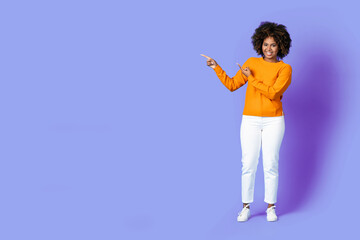 Full length of cheerful black lady pointing at copy space