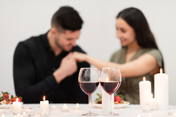 Two glasses with red wine over man kissing woman hand