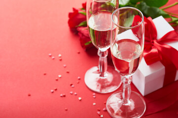 Valentines Day or Romantic dinner concept. Romantic table setting, silverware, wine glasses, gift box, roses and symbol of love red heart on red background. Romantic Dinner Valentines Day concept.