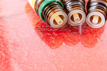 Three essential oil bottles on red corrugated glass, soft focus