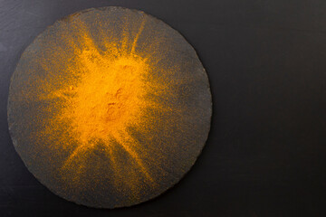 Orange curry powder explosion on black stone texture