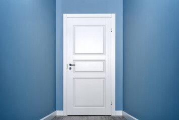 Closed white door in the empty corridor with blue walls, copy space