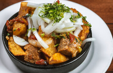 Beef stew with potatoes, carrots and herbs on black background with copy